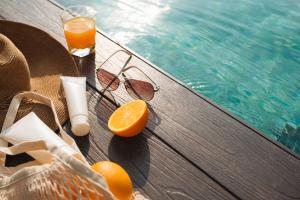 Beach hat, orange juice and sunglasses near the swimming pool