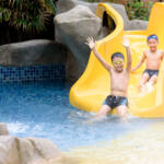 Young Asian Thai boy play water slider in a park during summer time.