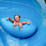 an 8 year old boy is riding in the water Park on inflatable circles on water slides.