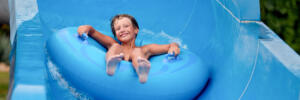 an 8 year old boy is riding in the water Park on inflatable circles on water slides.