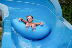 an 8 year old boy is riding in the water Park on inflatable circles on water slides.